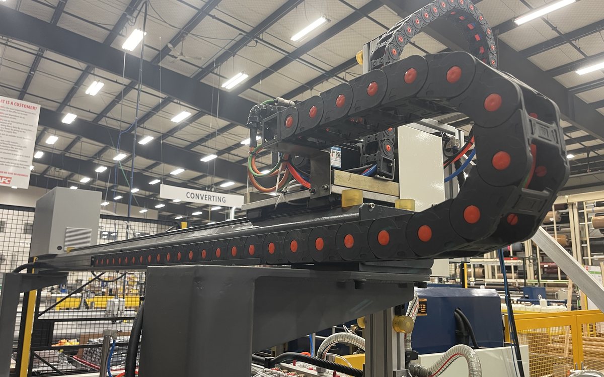Gantry automation axis with cable carrier above a production line